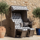 Strandkorb Trendy PURE Standard PE grey Dessin 478 mit Karo-Polster vor Steinmauer zwischen zwei Olivenbäumen auf Terrasse