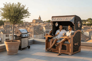 Strandkorb deVries Aruba XL Rope anthrazit Dessin 251, zwei Männer entspannen mit Getränken auf Dachterrasse mit Stadtblick