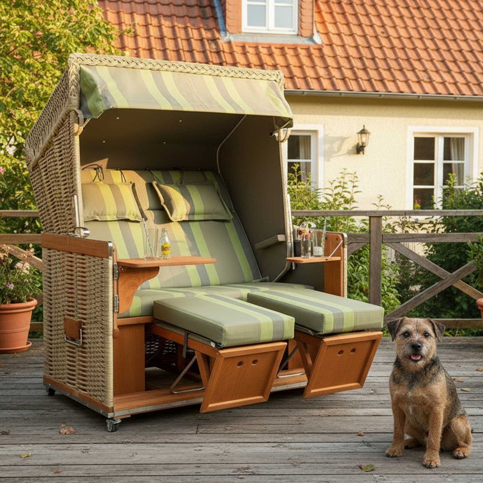 Strandkorb Konsul 2XL-Sitzer in grün mit komfortablem Innenraum und Hund auf der Terrasse.