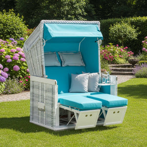 Strandkorb Konsul 2-Sitzer white-washed in türkis auf einer grünen Wiese mit Blumen im Hintergrund.