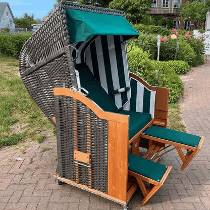 Strandkorb Sonnenpartner Classic anthrazit mit Holzgestell, grünem Polster und Fahrrollen auf Terrasse im Garten