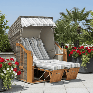 Strandkorb Sonnenpartner Classic Teak in Cappuccinooptik mit grau-taupe Streifenpolster auf Terrasse mit Blumen und Palmen